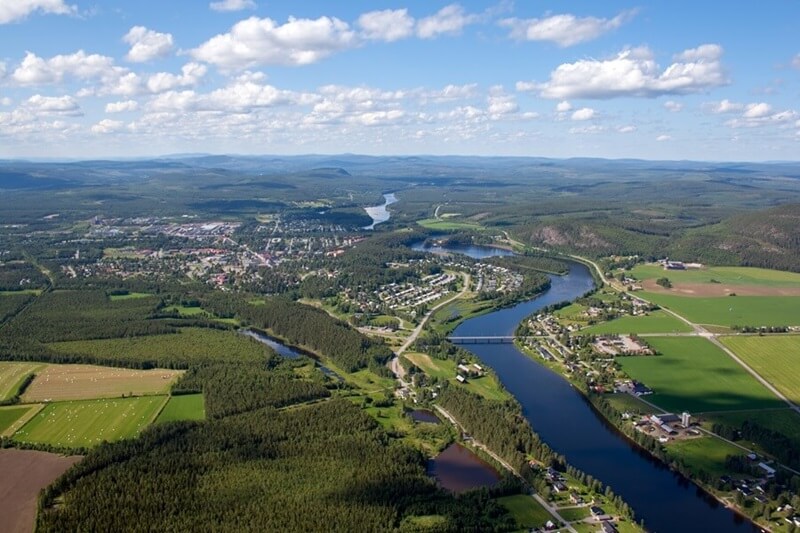 Fågelvy över Älvsbyn, Piteåälven som rinner fram och gröna landskap.